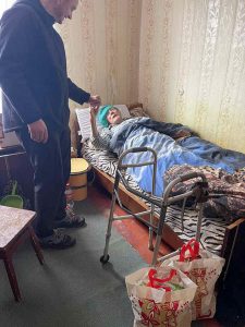 een oude vrouw in bed krijgt een voedselpakket van een vrijwilliger