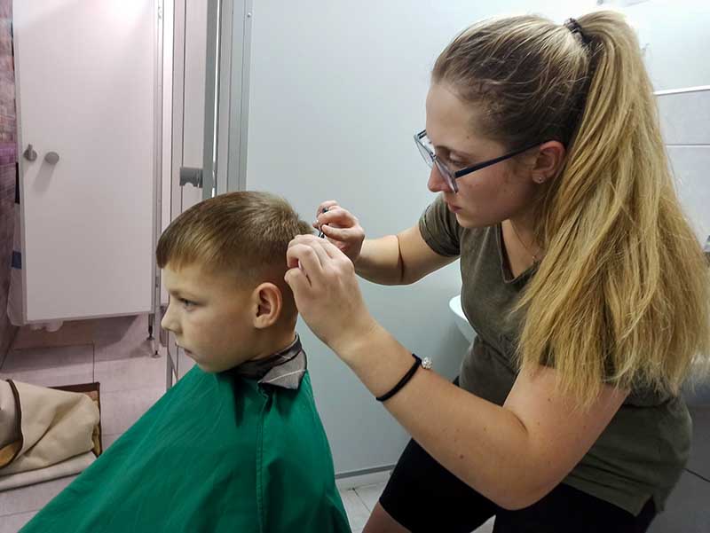 vrouw knipt het haar van een jongetje