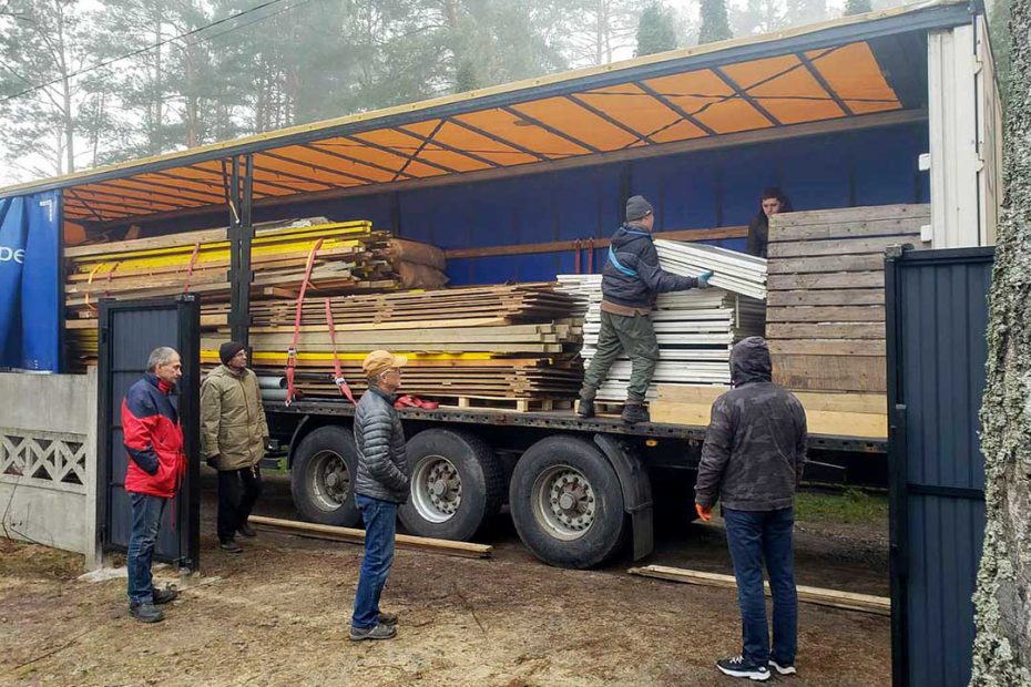 uitladen van de vrachtwagen met onderdelen voor de houten keet.