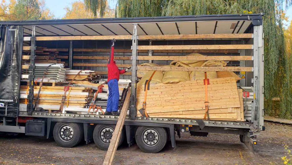 De vrachtwagen wordt geladen met houten onderdelen voor het huisje van het kinderkamp.